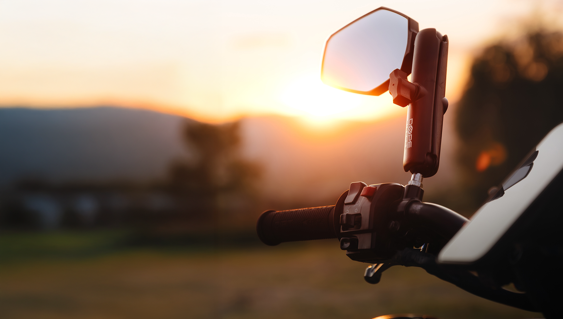 Lusterko DopeMirrors zamontowane na motocyklu adventure w tle zachodzącego słońca